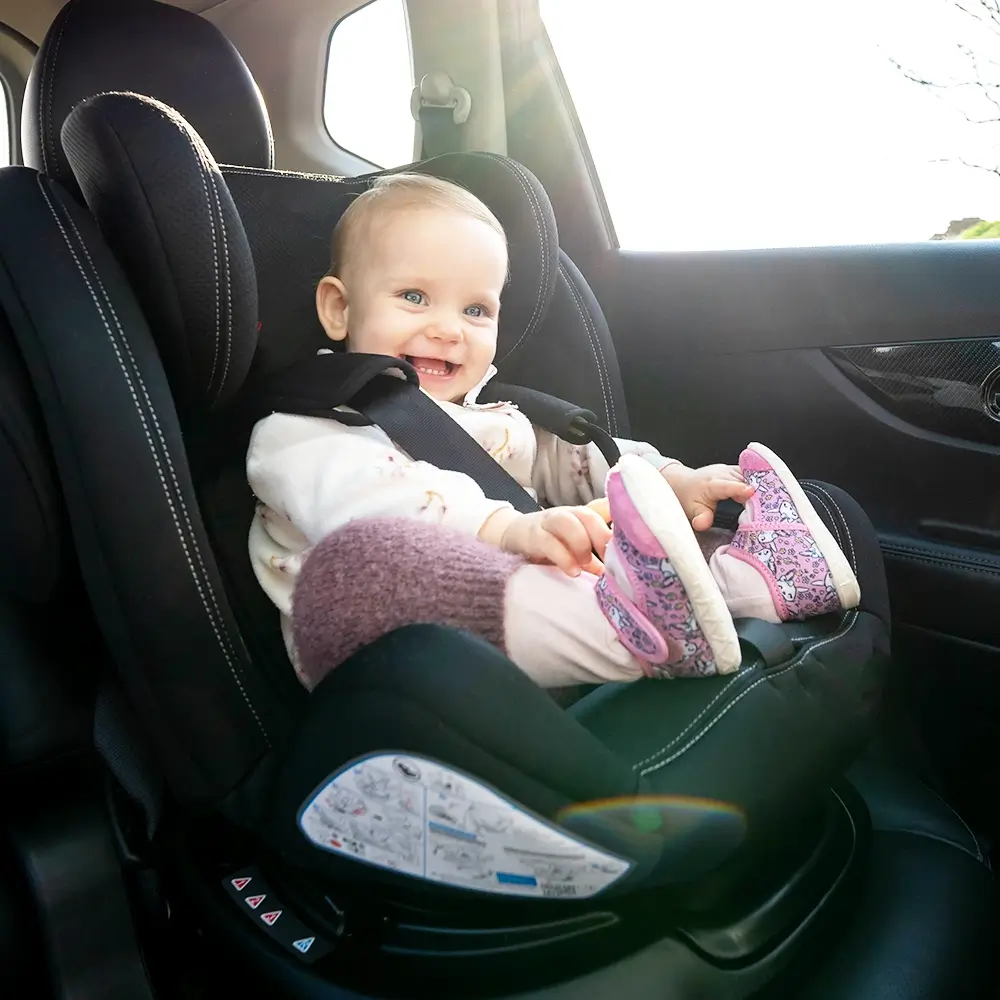 Smiling toddler strapped into a child car seat