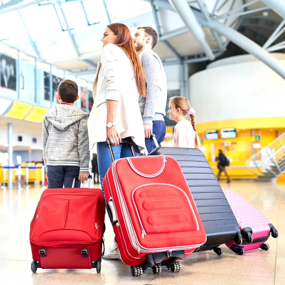 Family with suitcases walking through an airport terminal